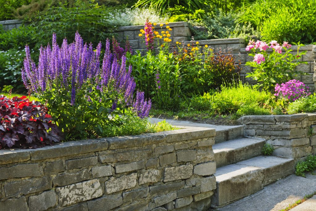 Neatly constructed segmental block retaining wall holding back a raised planting bed