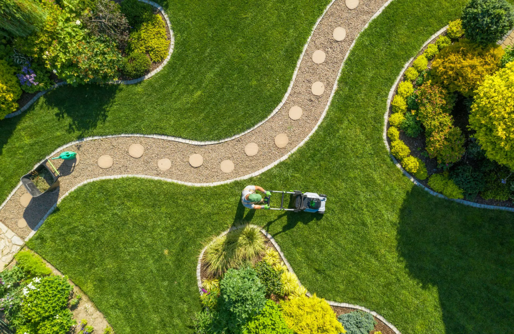 A wide view of a neatly maintained lawn with stepping stones, flower beds, and shrubs in a landscaped yard.